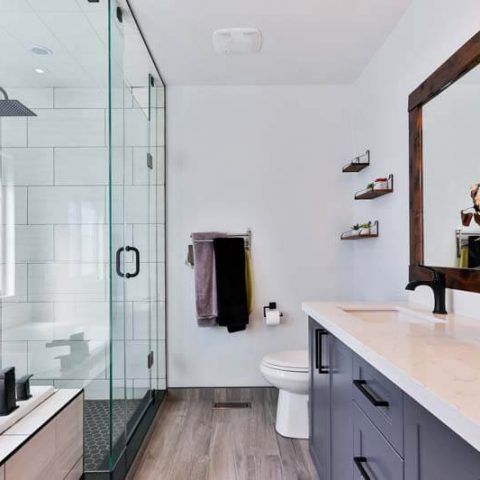 Modern bathroom with glass shower, toilet, floating vanity, and wood-framed mirror