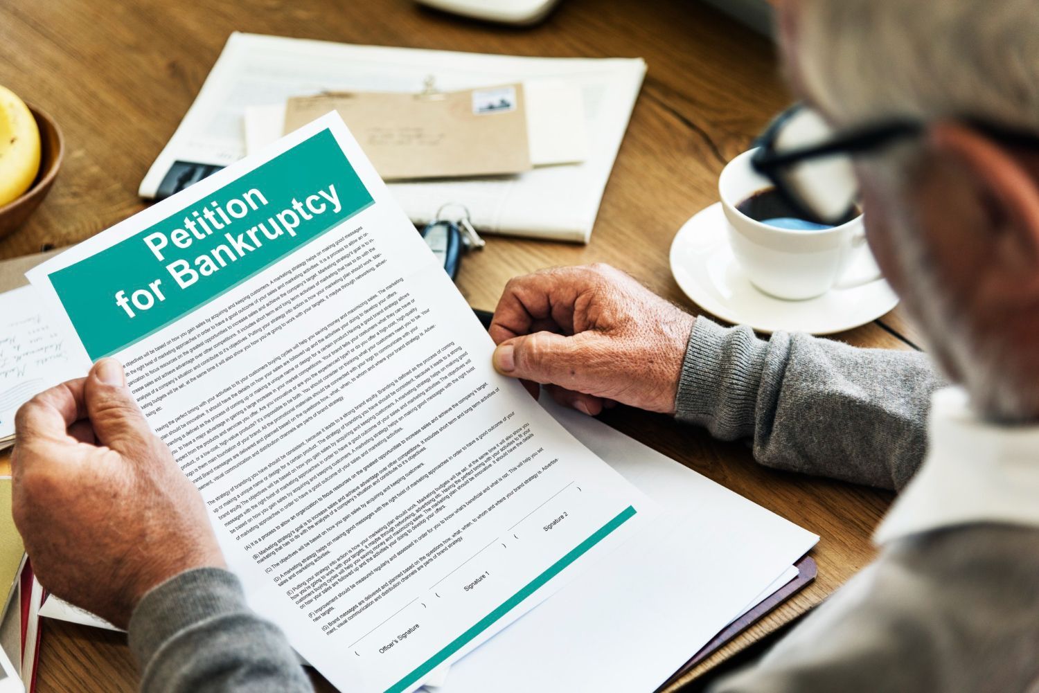 Person reviewing a bankruptcy petition form at a desk with papers and a coffee cup