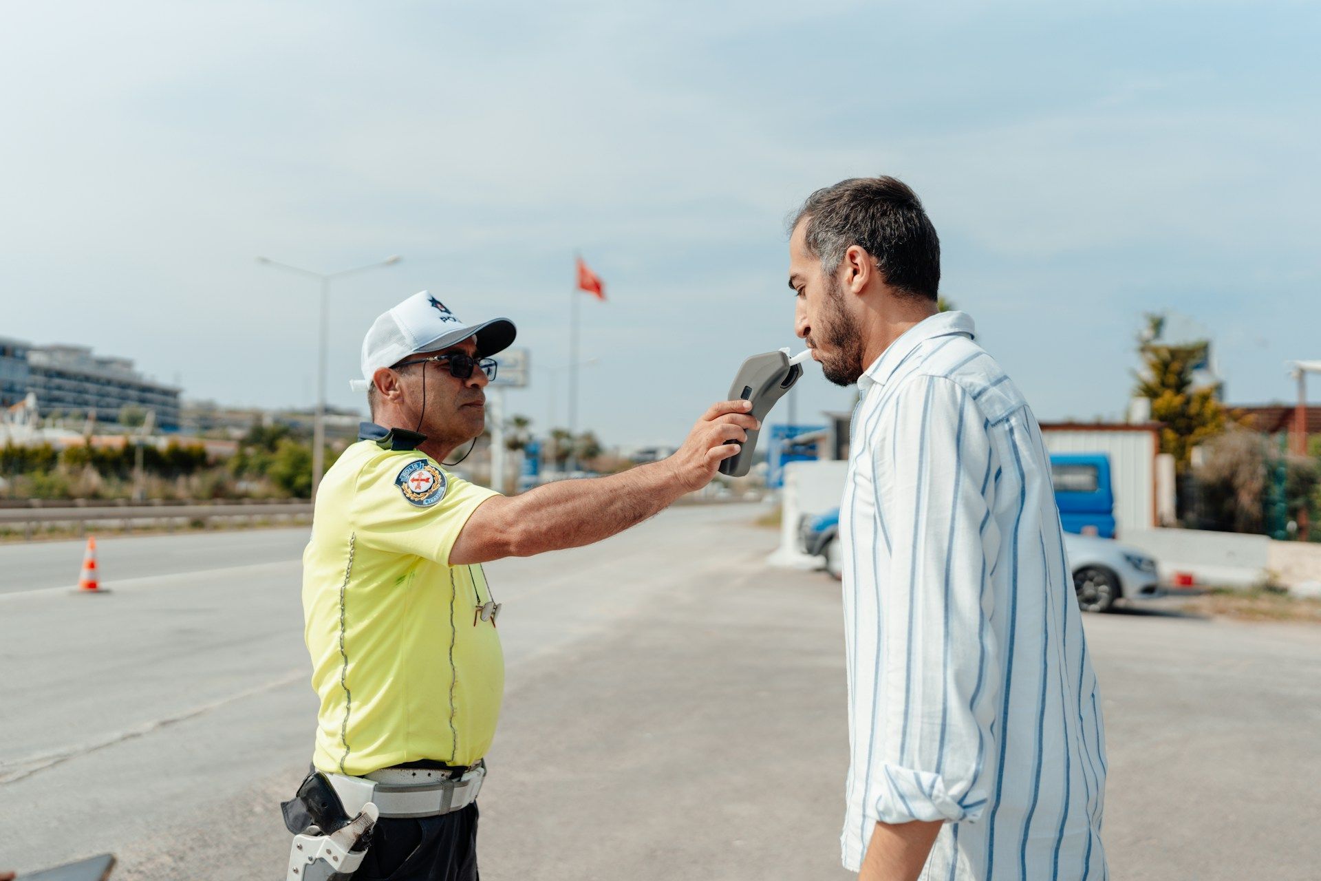 Traffic officer holding a handheld device toward a man on an open road during a roadside check