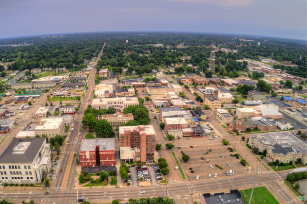 Aerial view of a small town with roads, buildings, parking lots, and trees stretching into the distance