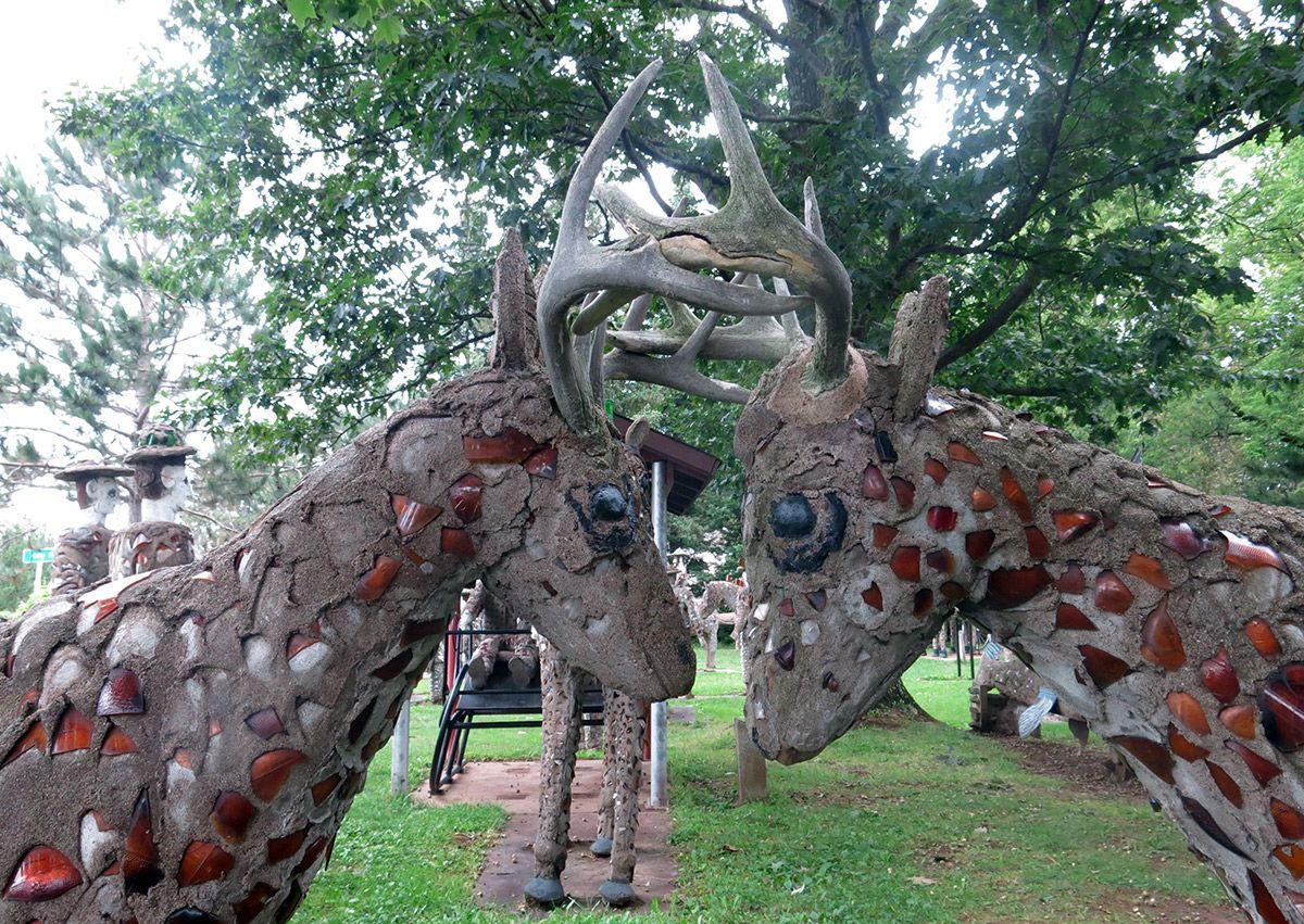 Two horned animal sculptures with red accents facing each other in a grassy park