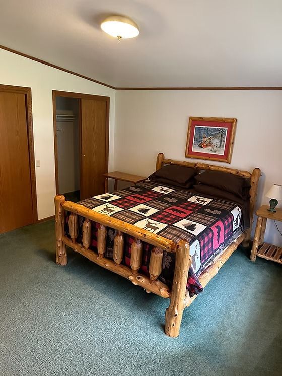 Bedroom with a log bed, closet, and a framed print on the wall. Green carpet.