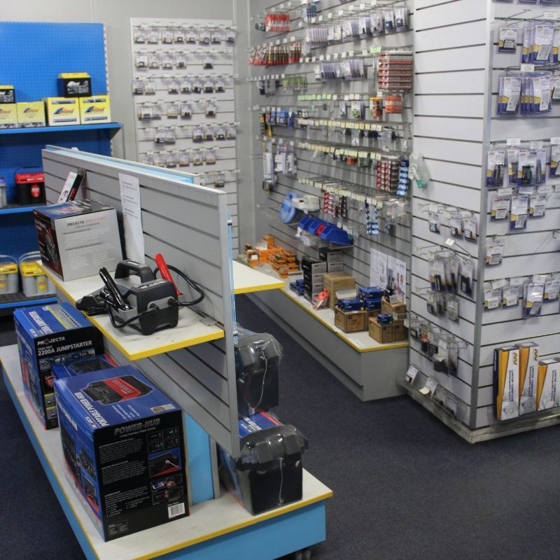 A hardware store aisle with tools and accessories displayed on white shelves and a carpeted floor.