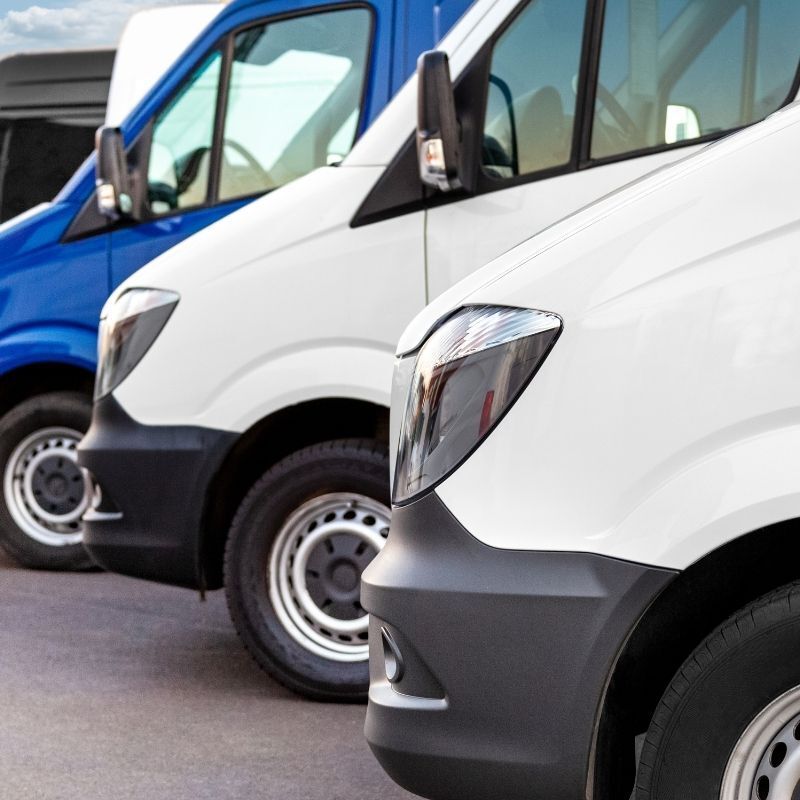 Blue and white delivery vans parked in a row on a street