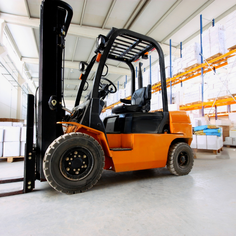 Orange forklift in a warehouse aisle, viewed from the side
