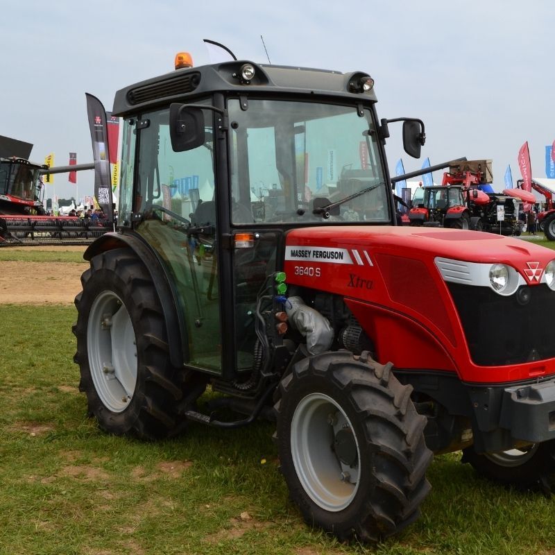 Red tractor parked on grass at an outdoor event, seen from the front-left.