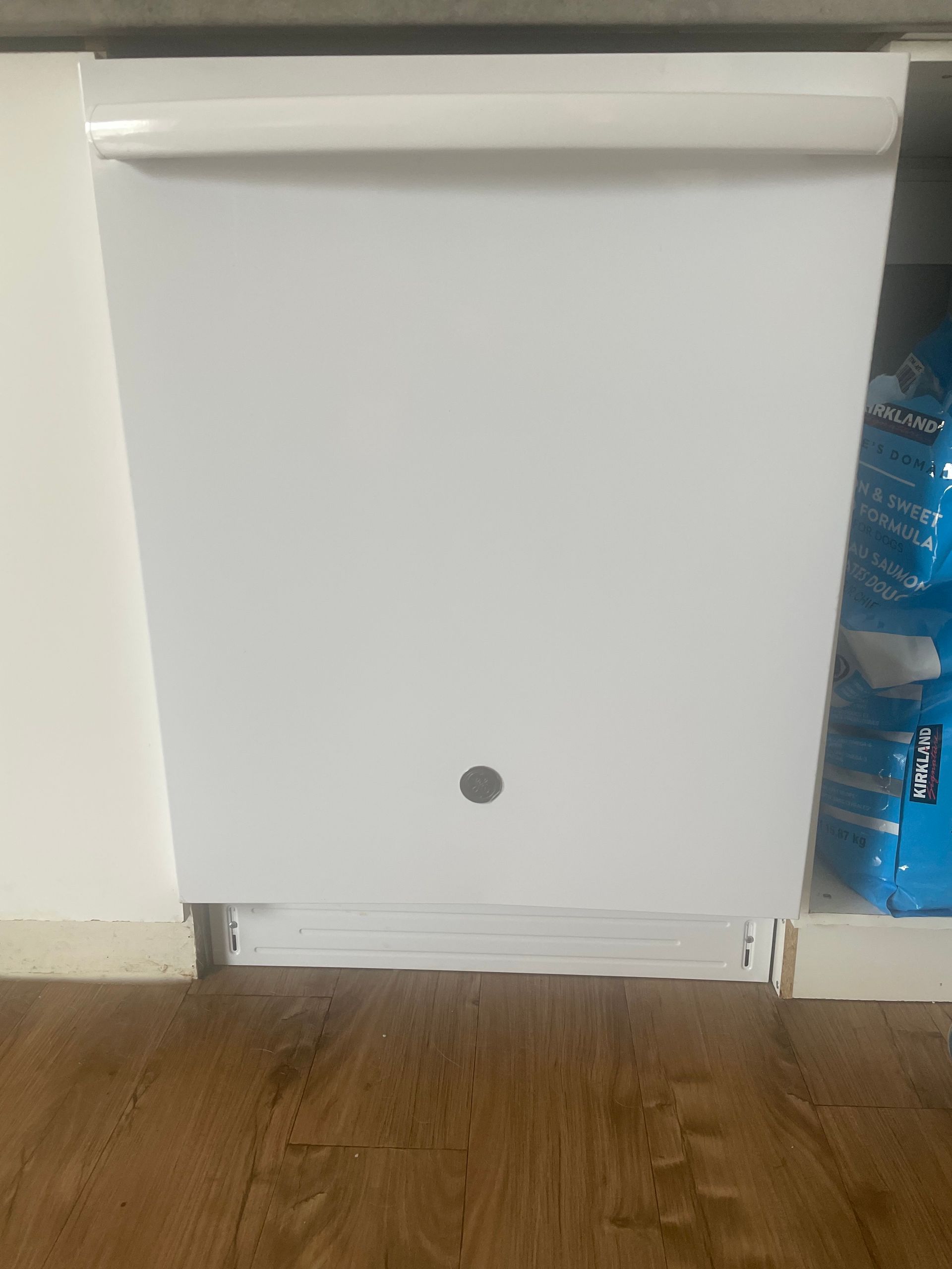 A white dishwasher is sitting under a cabinet in a kitchen.
