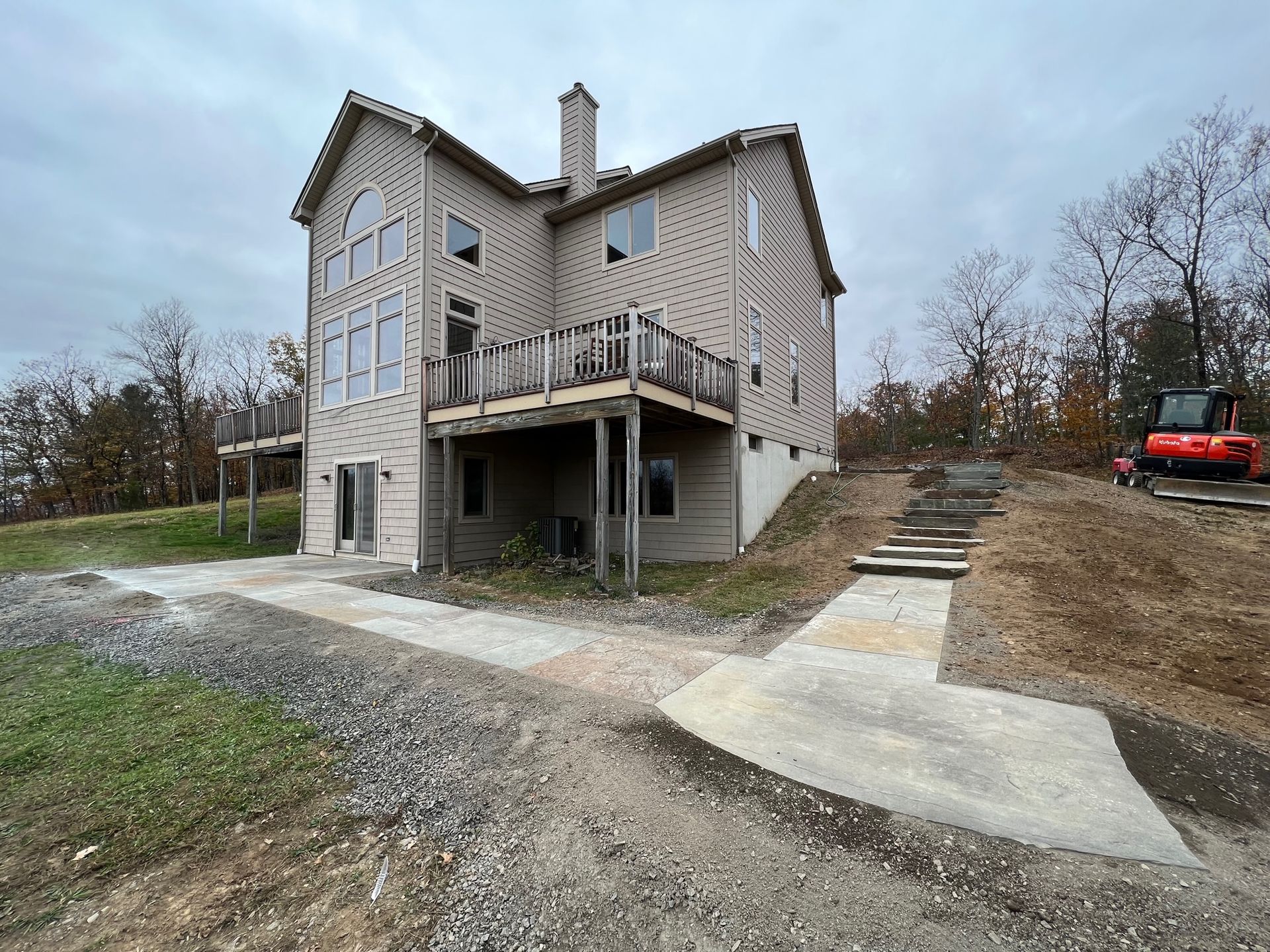 A large house is sitting on top of a dirt hill.