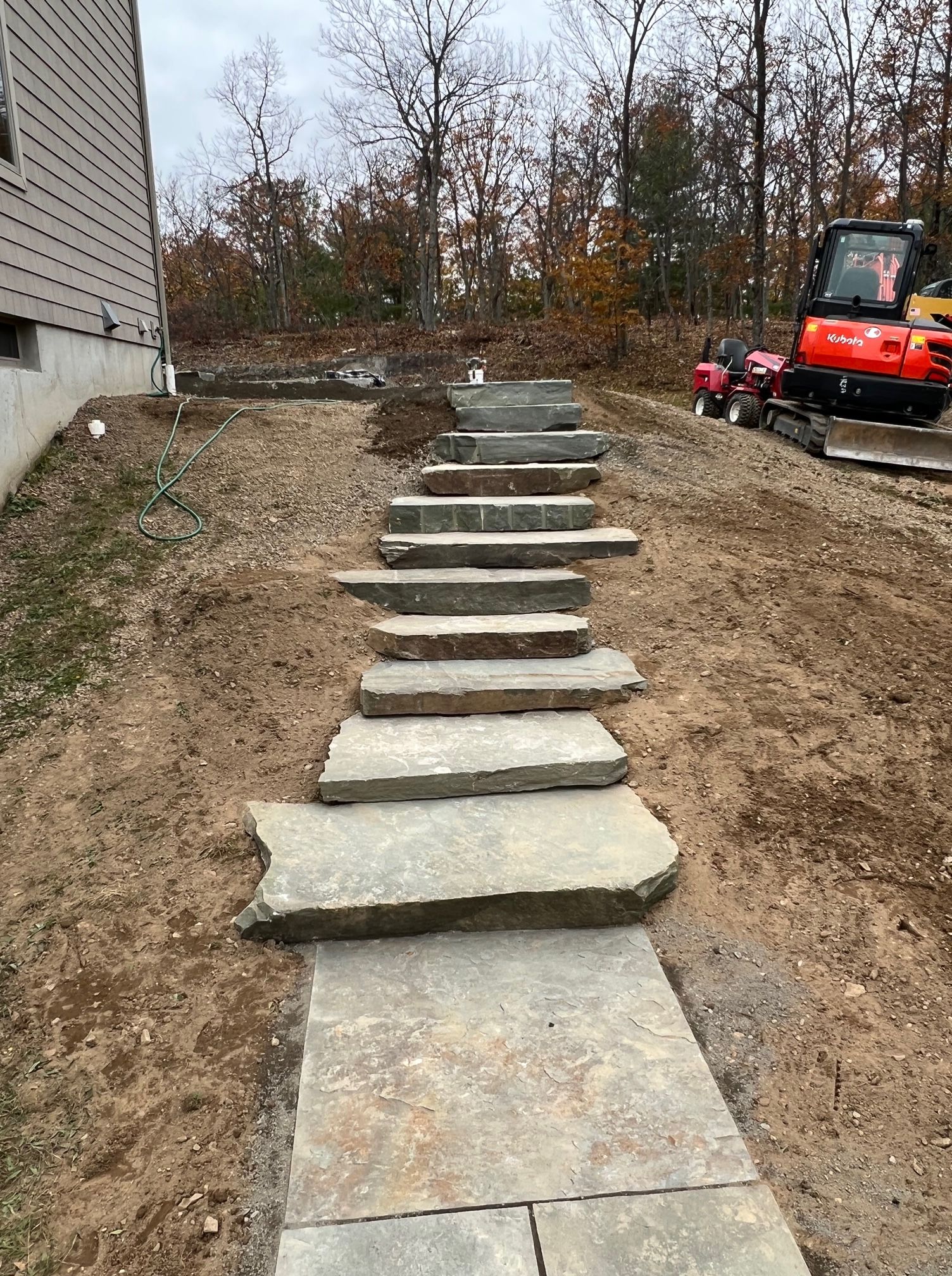 A set of stairs leading up to a house with a bulldozer in the background.