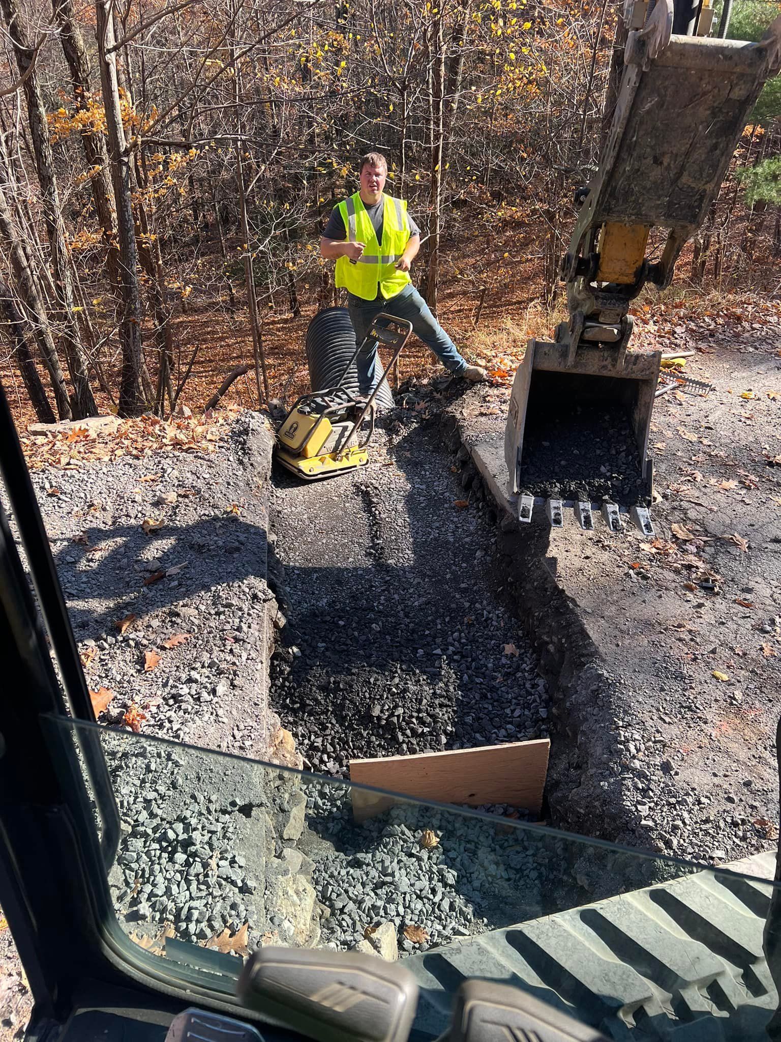 A man is sitting on the ground next to a bulldozer.