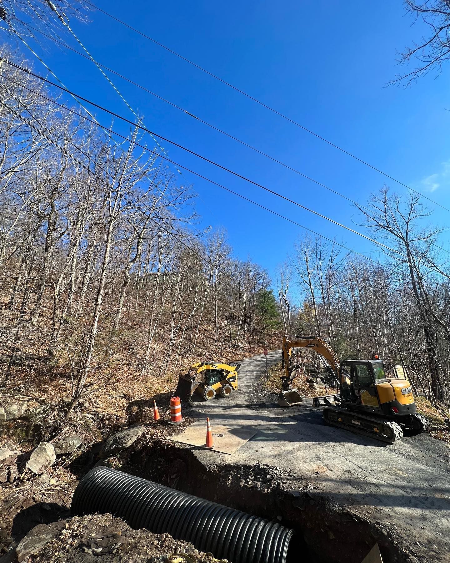 A yellow excavator is digging a hole in the middle of a dirt road.