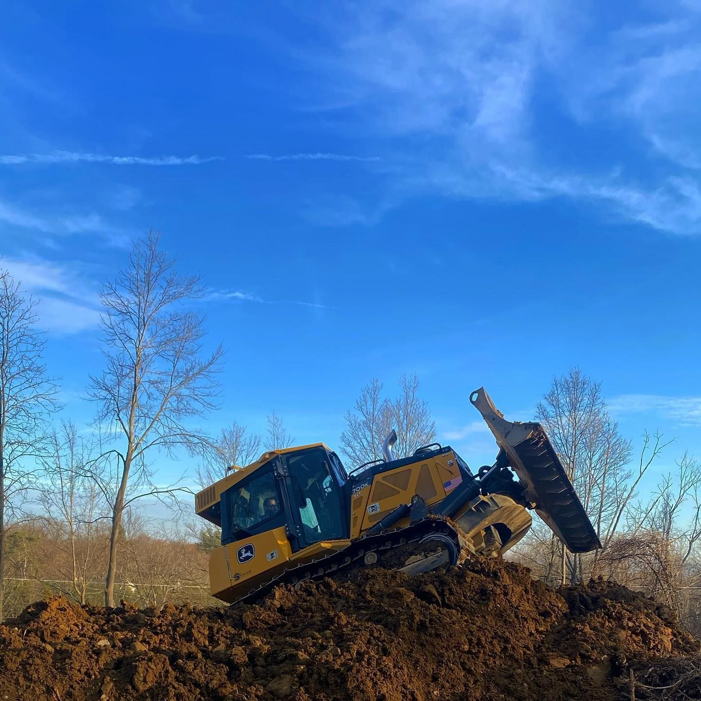 A bulldozer is sitting on top of a pile of dirt.