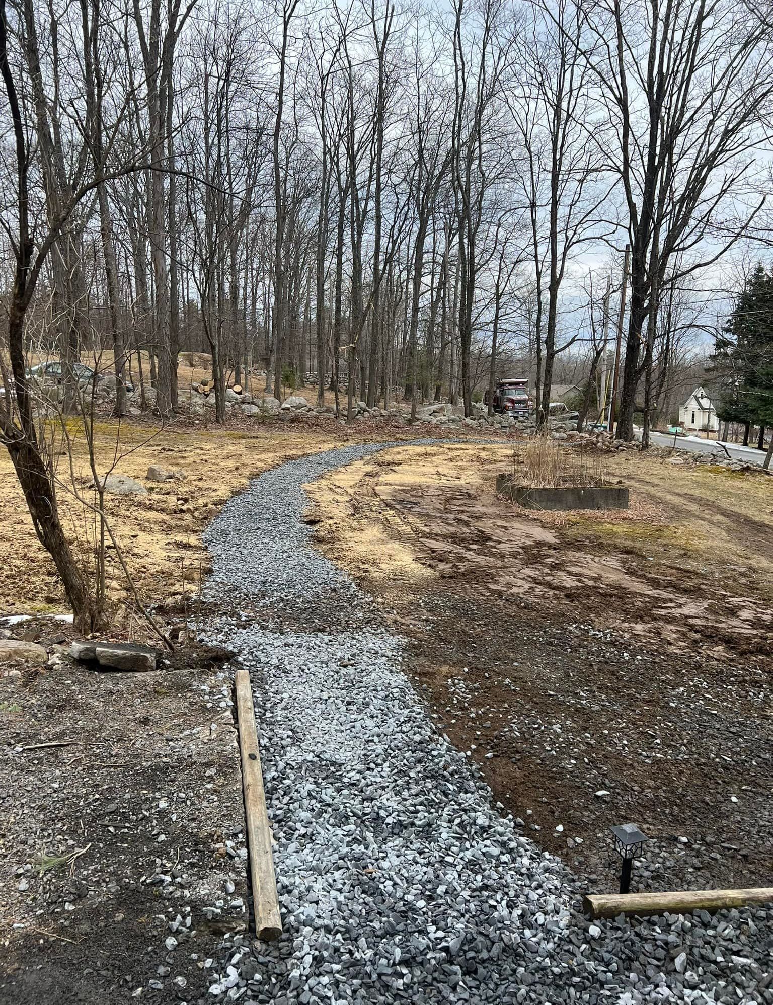 A gravel path going through a forest with trees in the background.