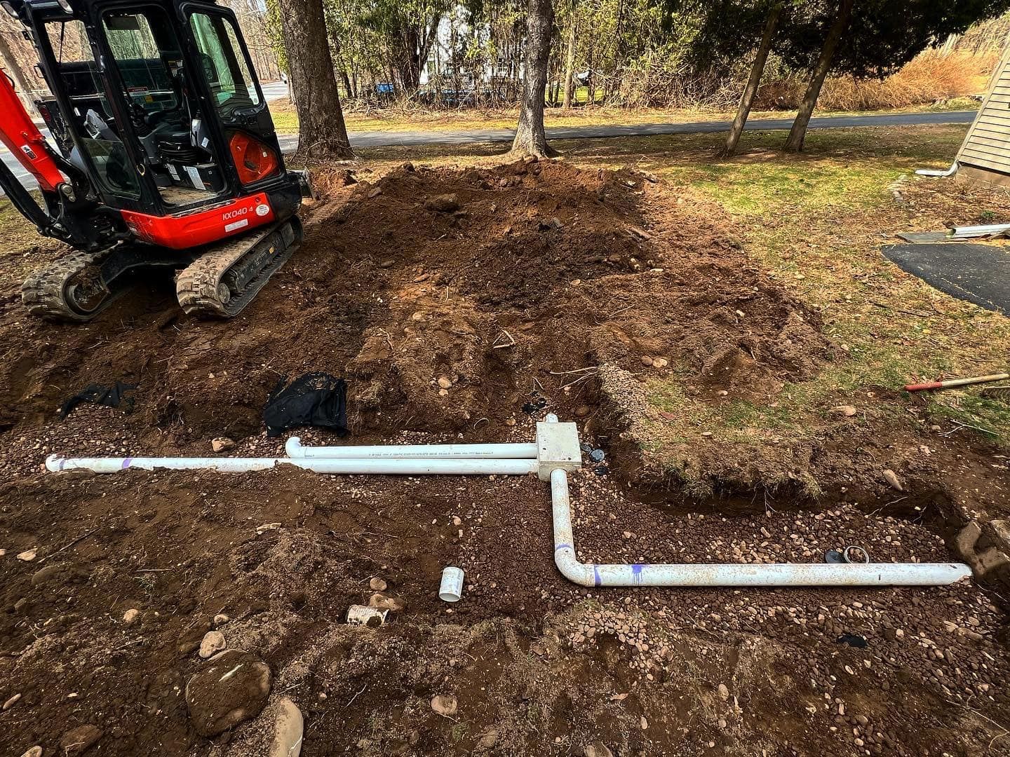 A small excavator is digging a hole in the ground next to a pile of dirt.