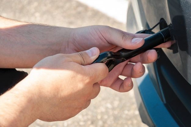 Hands Using a Black Tool to Open a Car's Gas Tank — Best Price Towing in Gosford, NSW