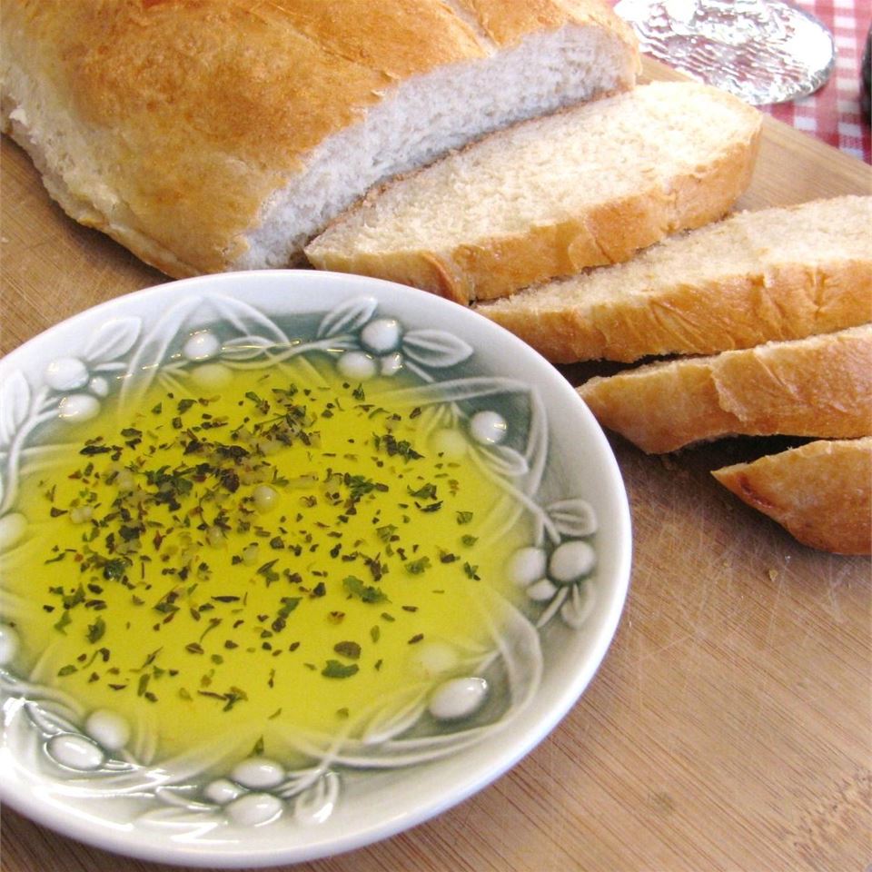 A sliced loaf of bread next to a bowl of dipping sauce