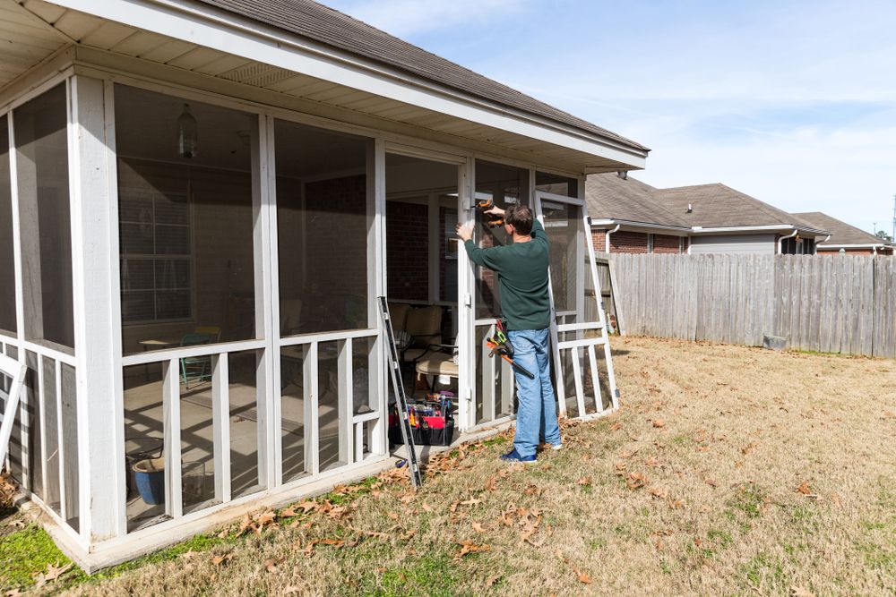 A Man Is Installing A Screened In Porch Door On A House — Auslinc Building Services In Wingham, NSW