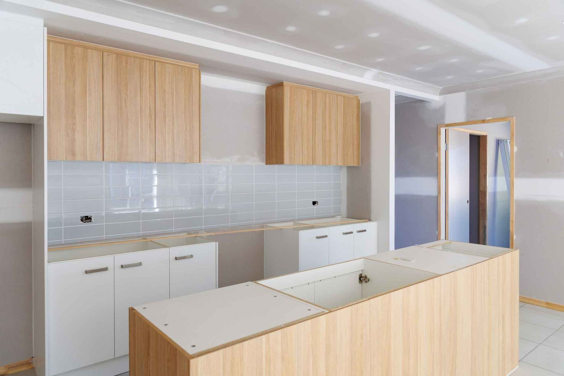 An Empty Kitchen With Wooden Cabinets And A Large Island — Auslinc Building Services In Wingham, NSW