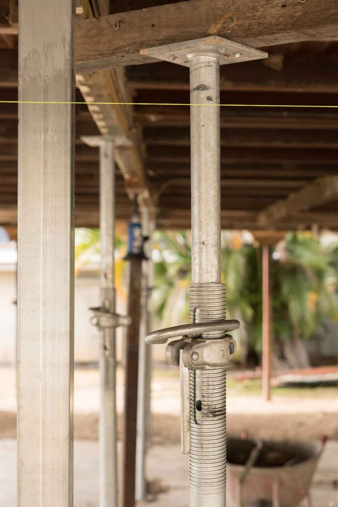 A Row Of Metal Poles Sitting On Top Of A Wooden Floor — Auslinc Building Services In Wingham, NSW