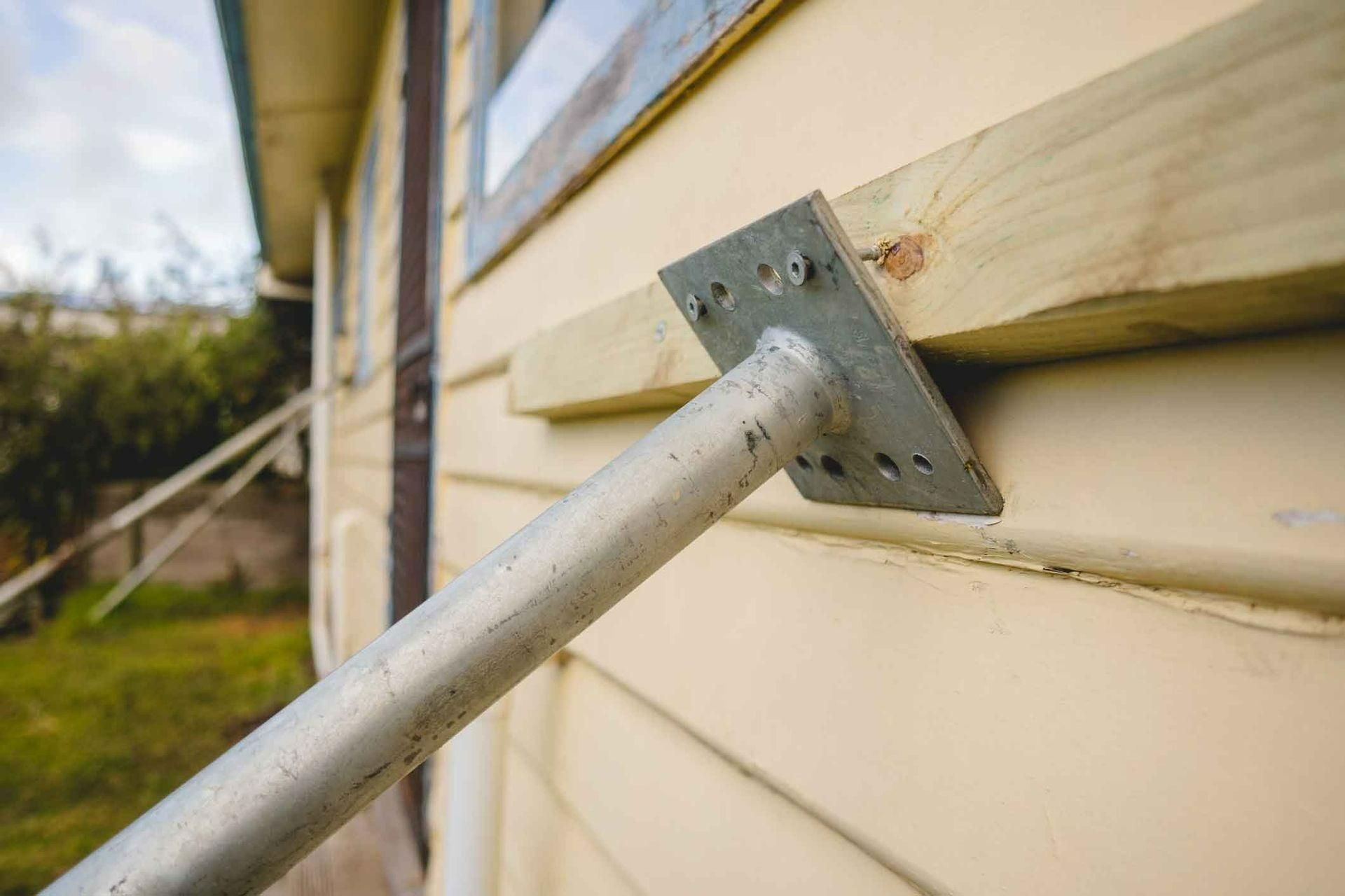 A Metal Pole Is Attached To A Wooden Beam On The Side Of A House β Auslinc Building Services In Wingham, NSW