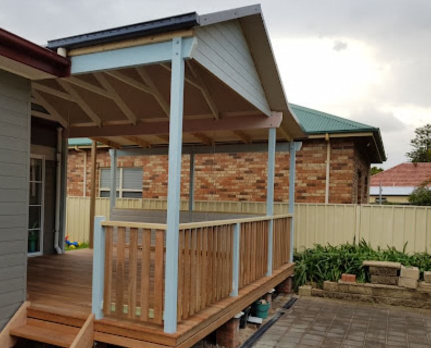 A Wooden Deck With A Roof Is Sitting In Front Of A Brick House — Auslinc Building Services In Wingham, NSW