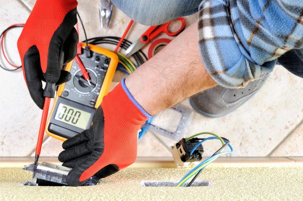 A Man Is Using A Multimeter To Test A Wire — L.A.F Electrical P/L In Terrigal, NSW