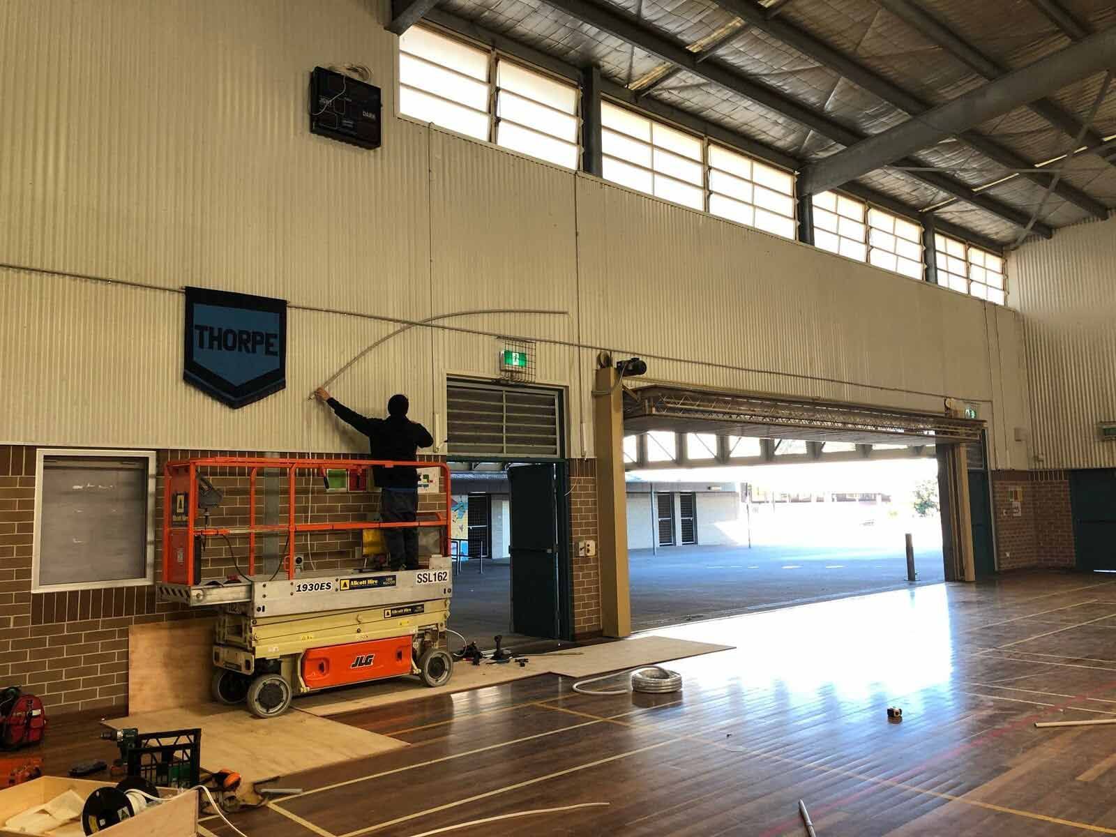 A Man Is Standing On A Lift In A Gym — L.A.F Electrical P/L In Empire Bay, NSW