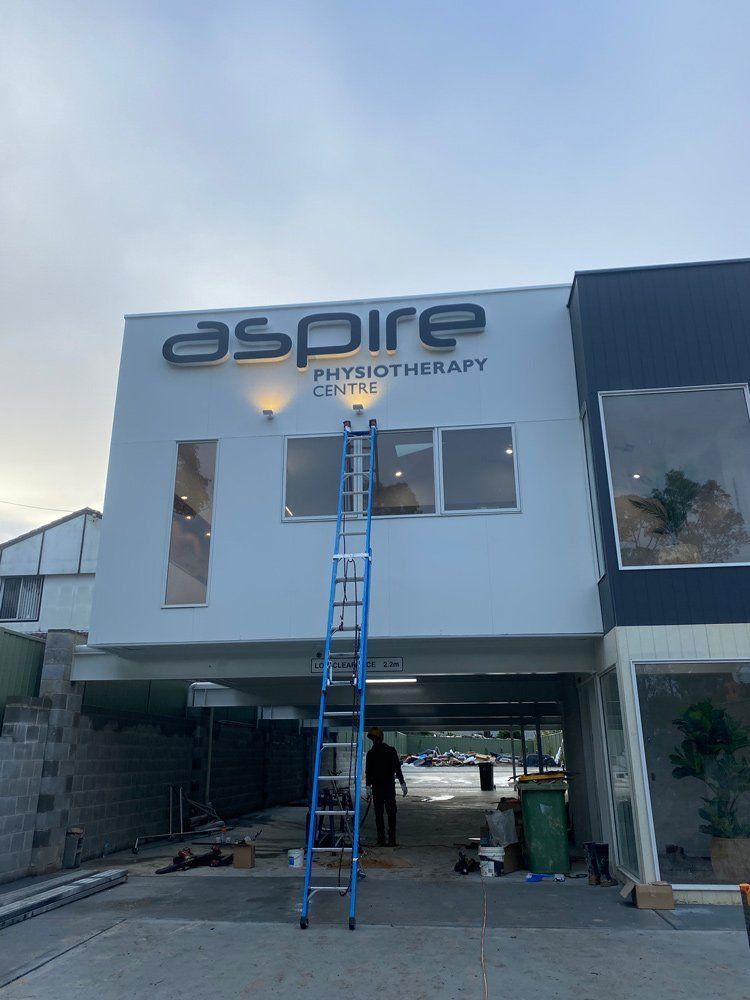A Man Is Standing On A Ladder In Front Of A Building — L.A.F Electrical P/L In Terrigal, NSW