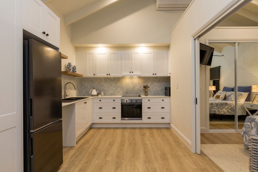 A Kitchen With White Cabinets And A Black Refrigerator — L.A.F Electrical P/L In Terrigal, NSW