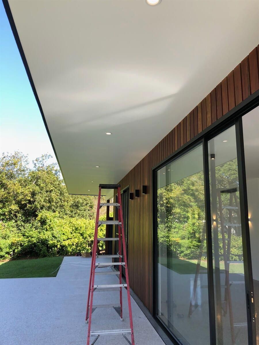 A Ladder Is Sitting Outside Of A House With Sliding Glass Doors — L.A.F Electrical P/L In Umina, NSW