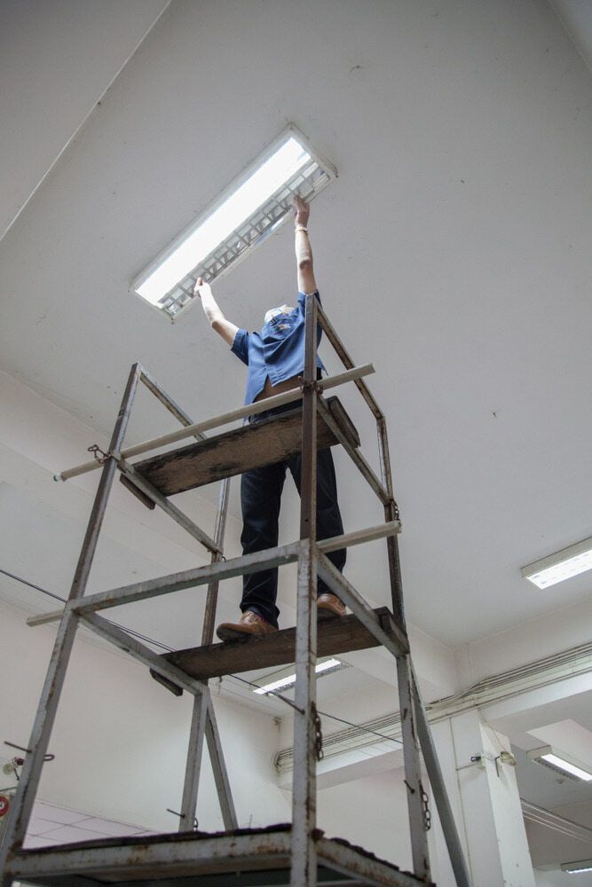 A Man Is Standing On A Scaffolding Fixing A Light Fixture — L.A.F Electrical P/L In Bateau Bay, NSW