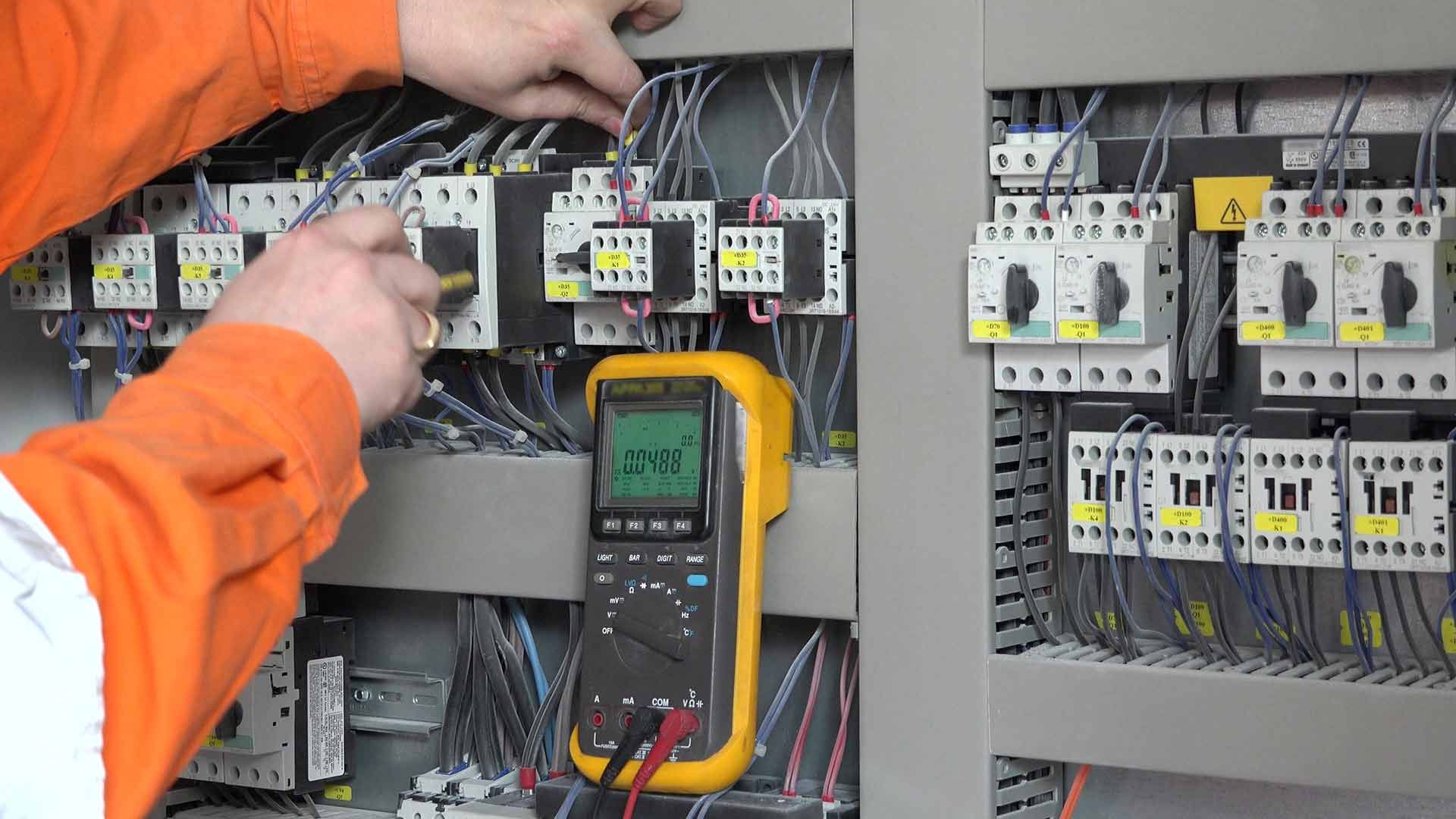 A Man Is Working On An Electrical Panel With A Fluke Multimeter — L.A.F Electrical P/L In Terrigal, NSW