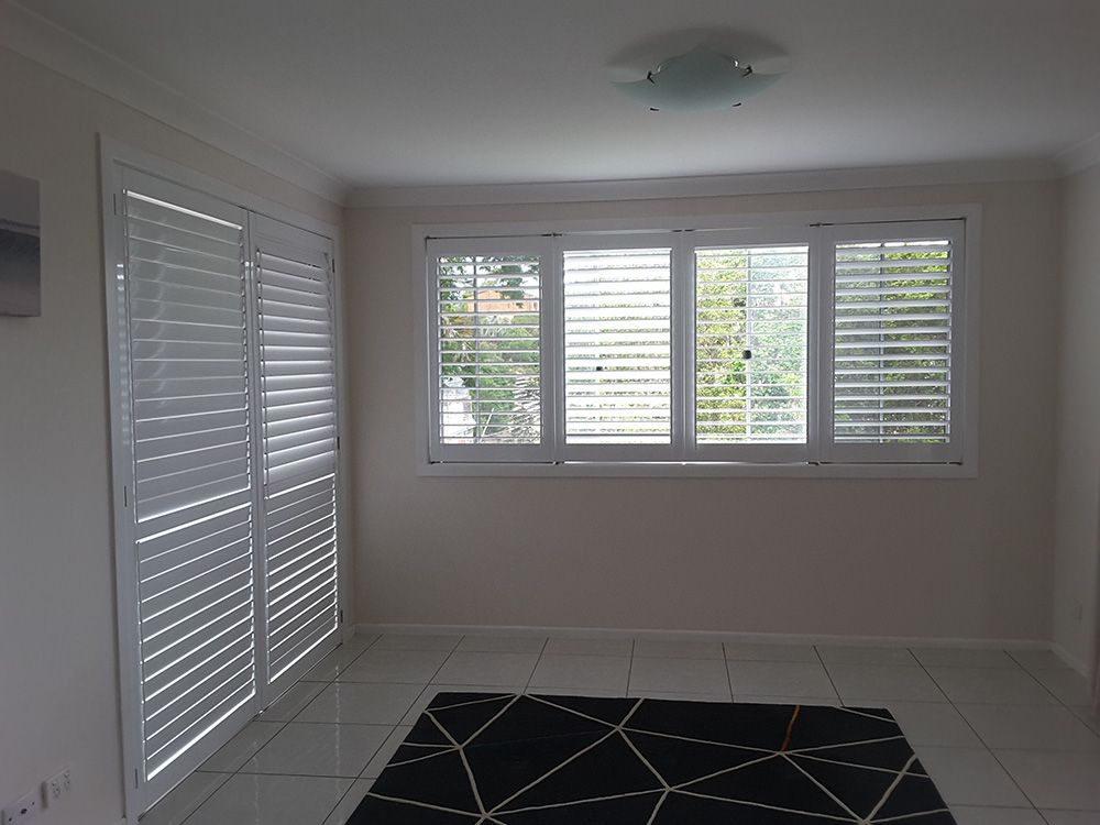 A Living Room With White Shutters on The Windows and a Black Rug — Whitsunday Blinds & Security In Beaconsfield, QLD