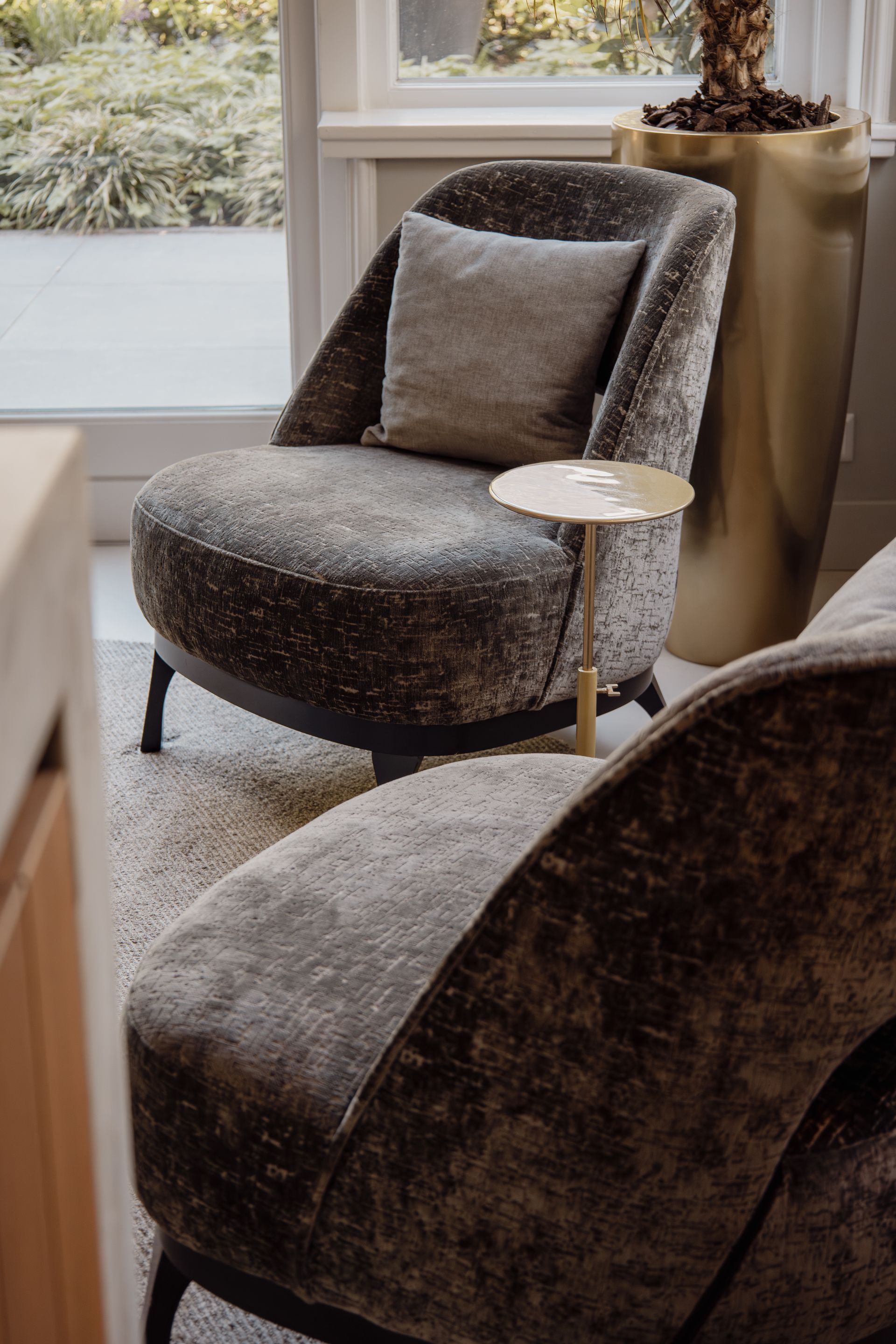 Gezellige fauteuils in donkere, gestructureerde stof naast een raam en een klein bijzettafeltje.