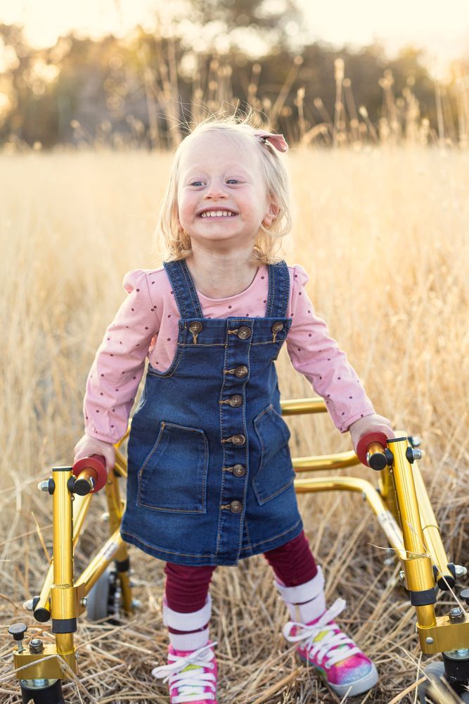 Smiling young girl standing with the aid of a specialised walking frame - First Aid in Mackay, QLD 