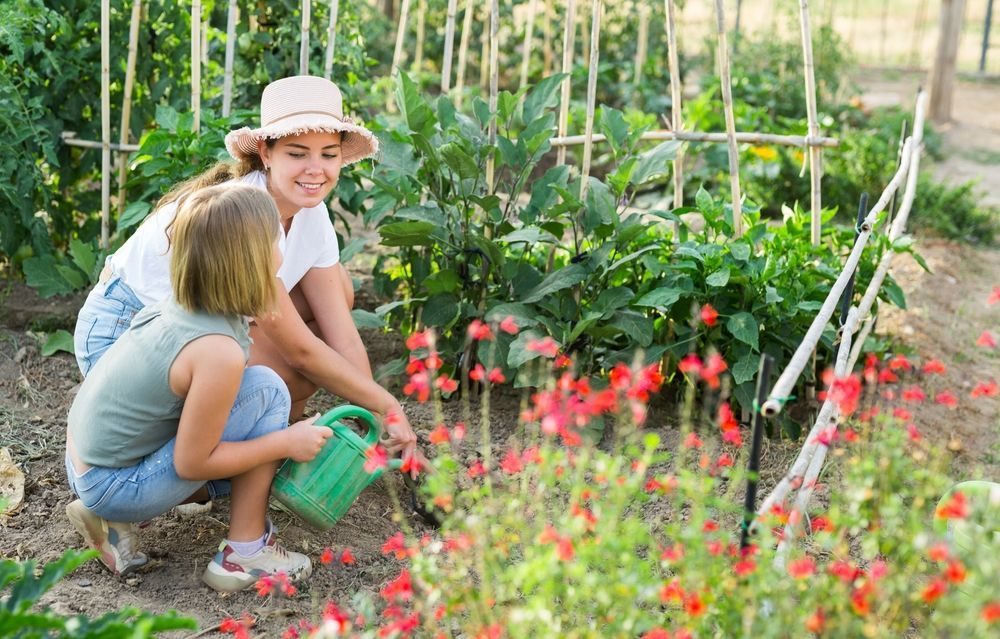 Daughter assisting her mother to water plants with a watering can - First Aid in Mackay, QLD