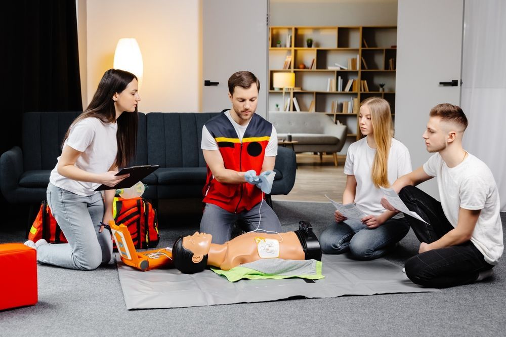 Young Man Instructor Helping to Make First Aid Heart Compressions with Dummy - First Aid in Mackay, QLD