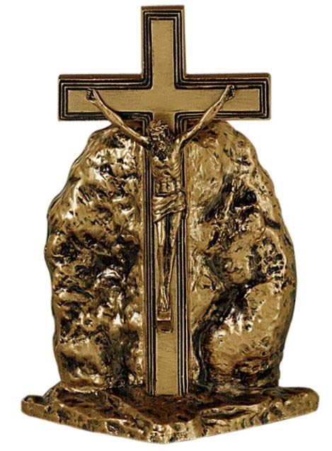 A bronze cross with jesus on it is sitting on top of a rock.