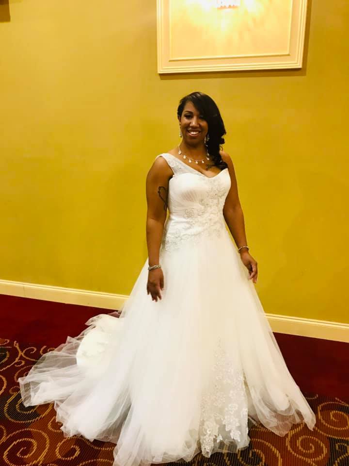 A woman in a white wedding dress is standing on a red carpet.