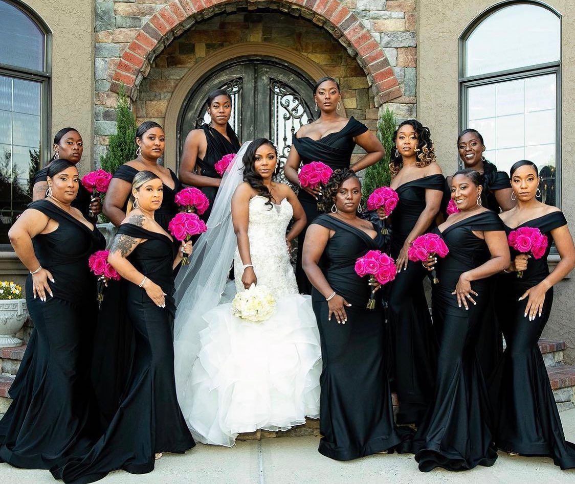 A bride and her bridesmaids are posing for a picture in front of a building.