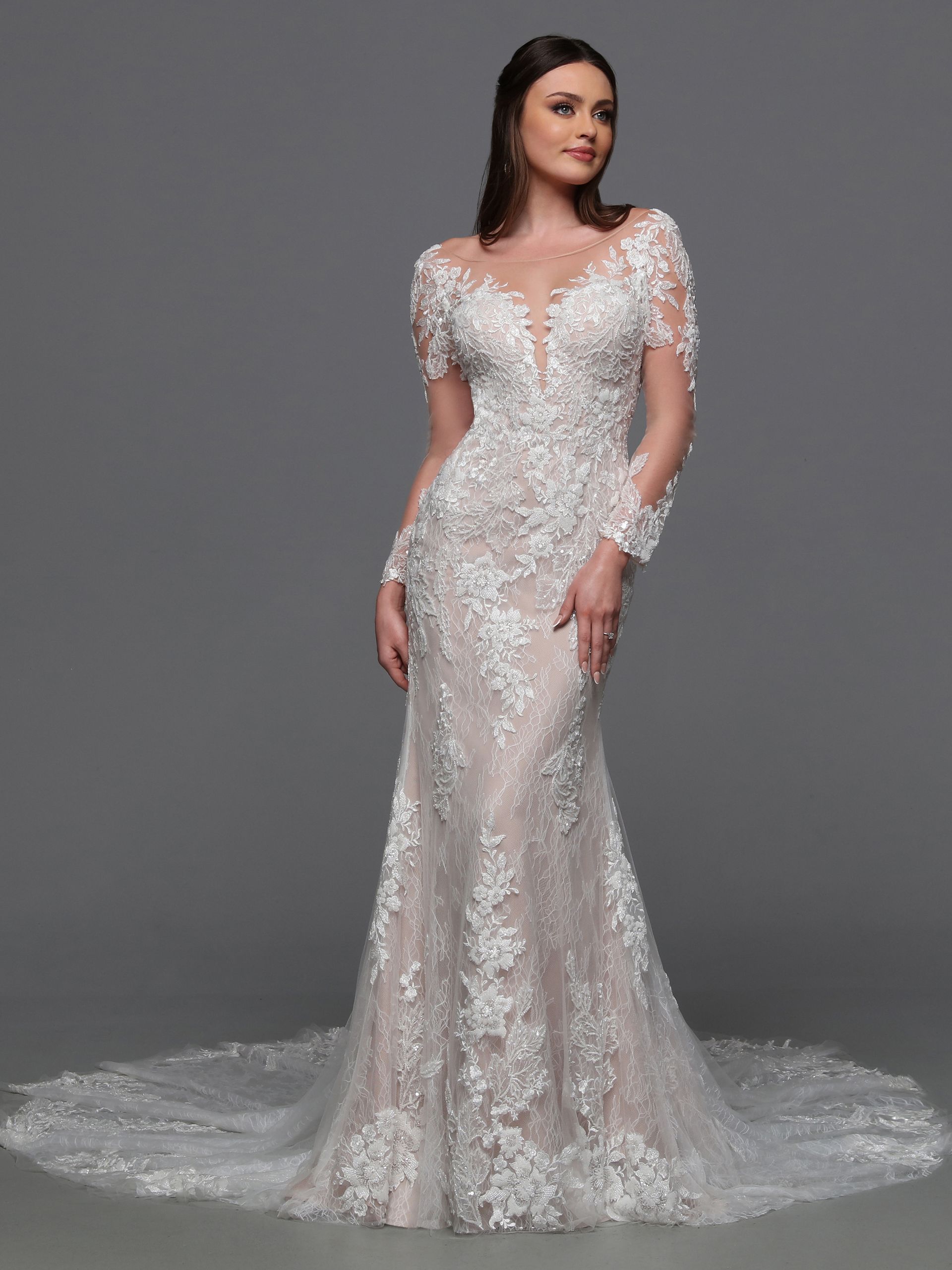 A woman is wearing a white lace wedding dress with long sleeves.