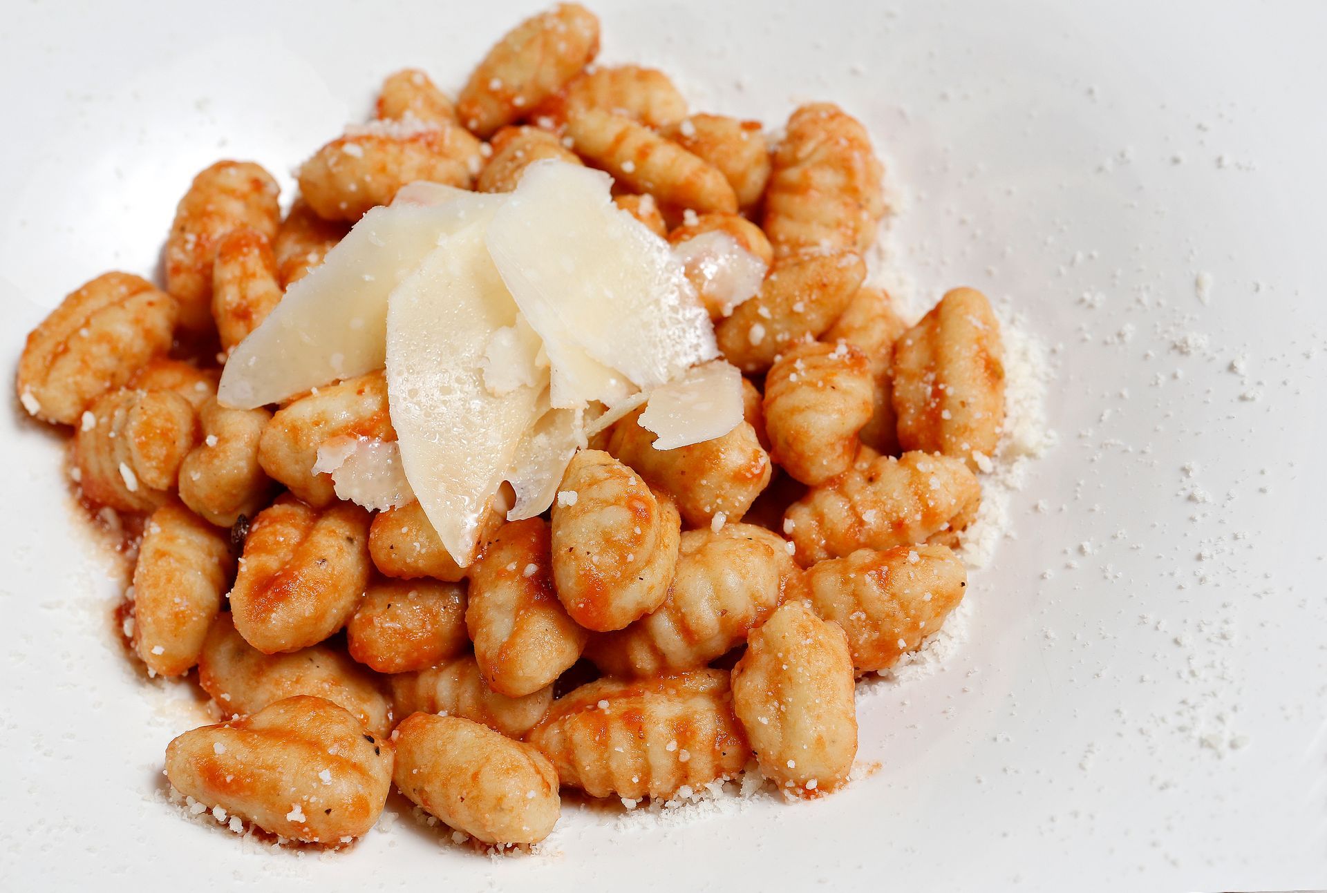 A white plate topped with gnocchi and cheese.