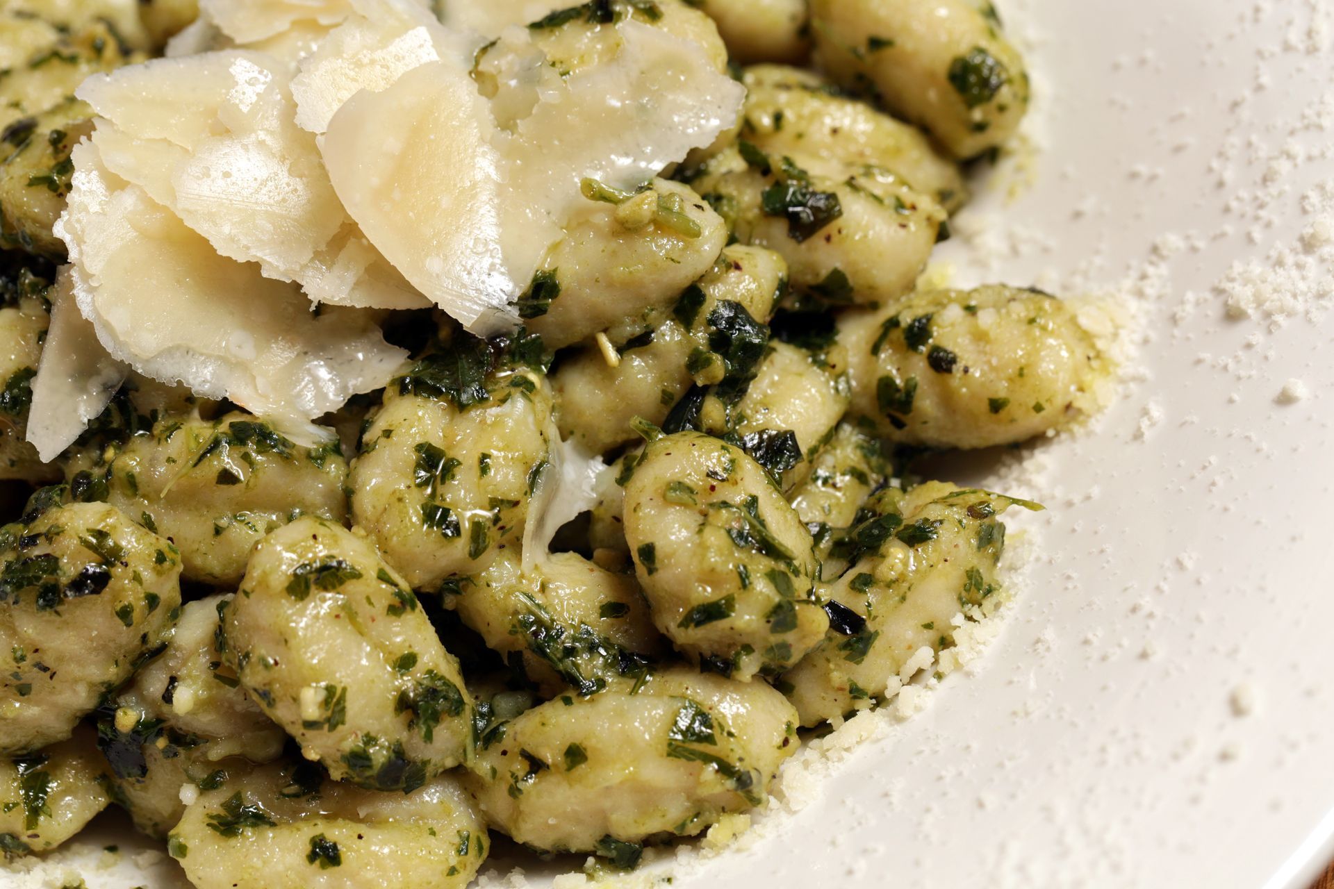 A white plate topped with gnocchi and parmesan cheese.
