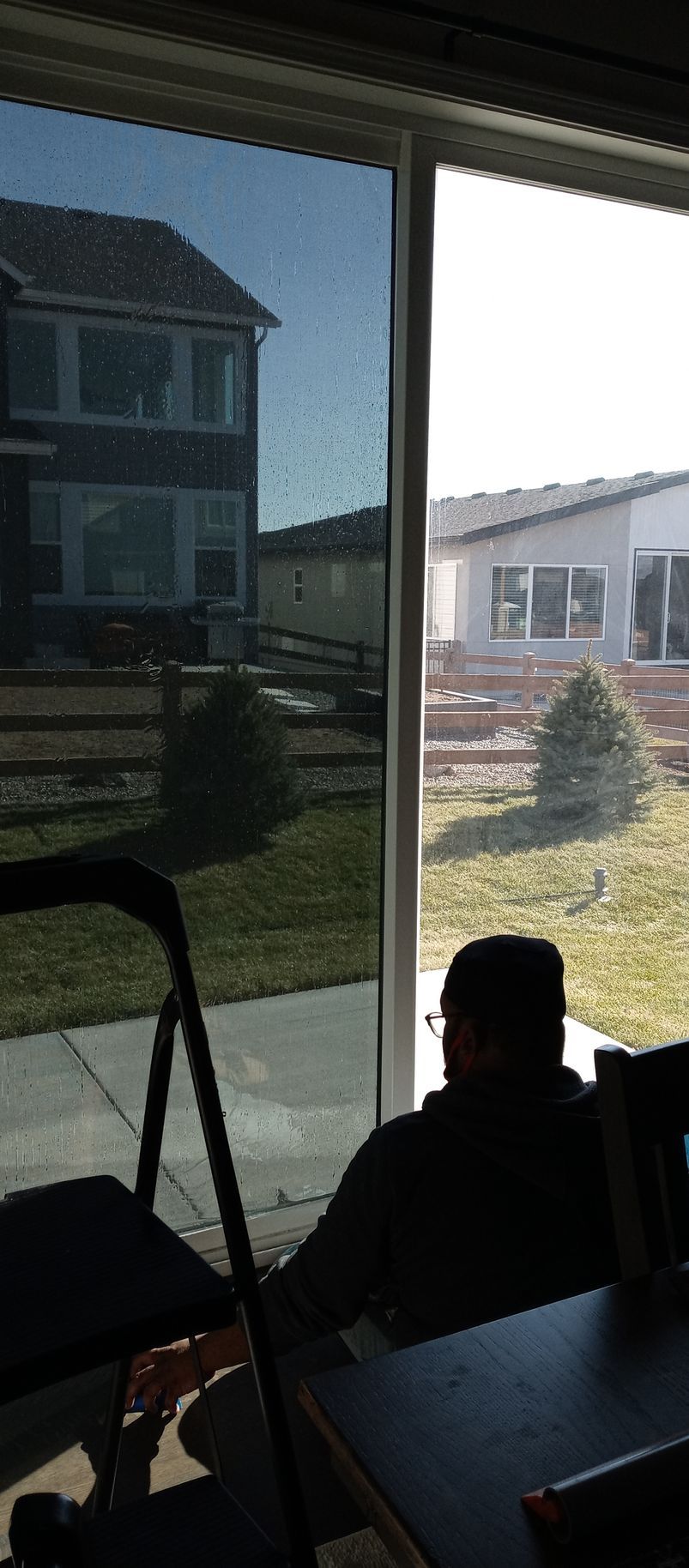 A man is installing window tint on a sliding glass door at a house.