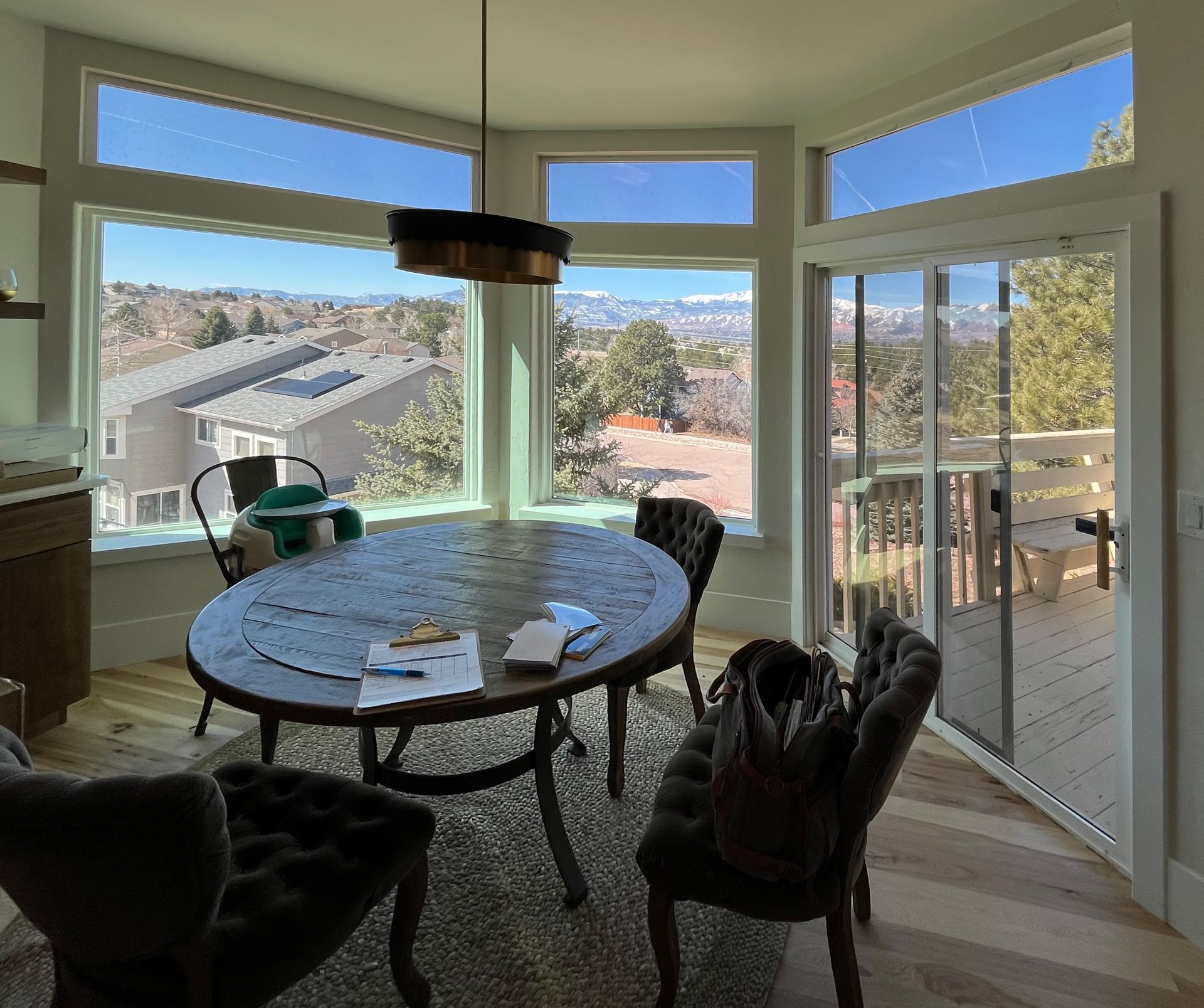 A dining room with a table and chairs and  large tinted windows with a view of the mountains