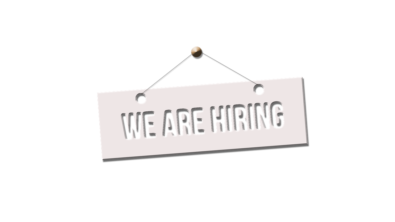 A sign that says we are hiring is hanging on a string.