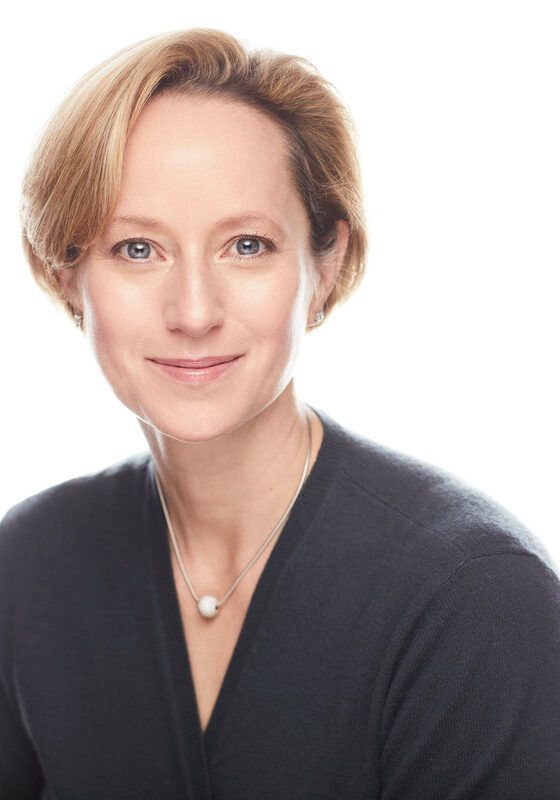 A woman wearing a black sweater and a pearl necklace