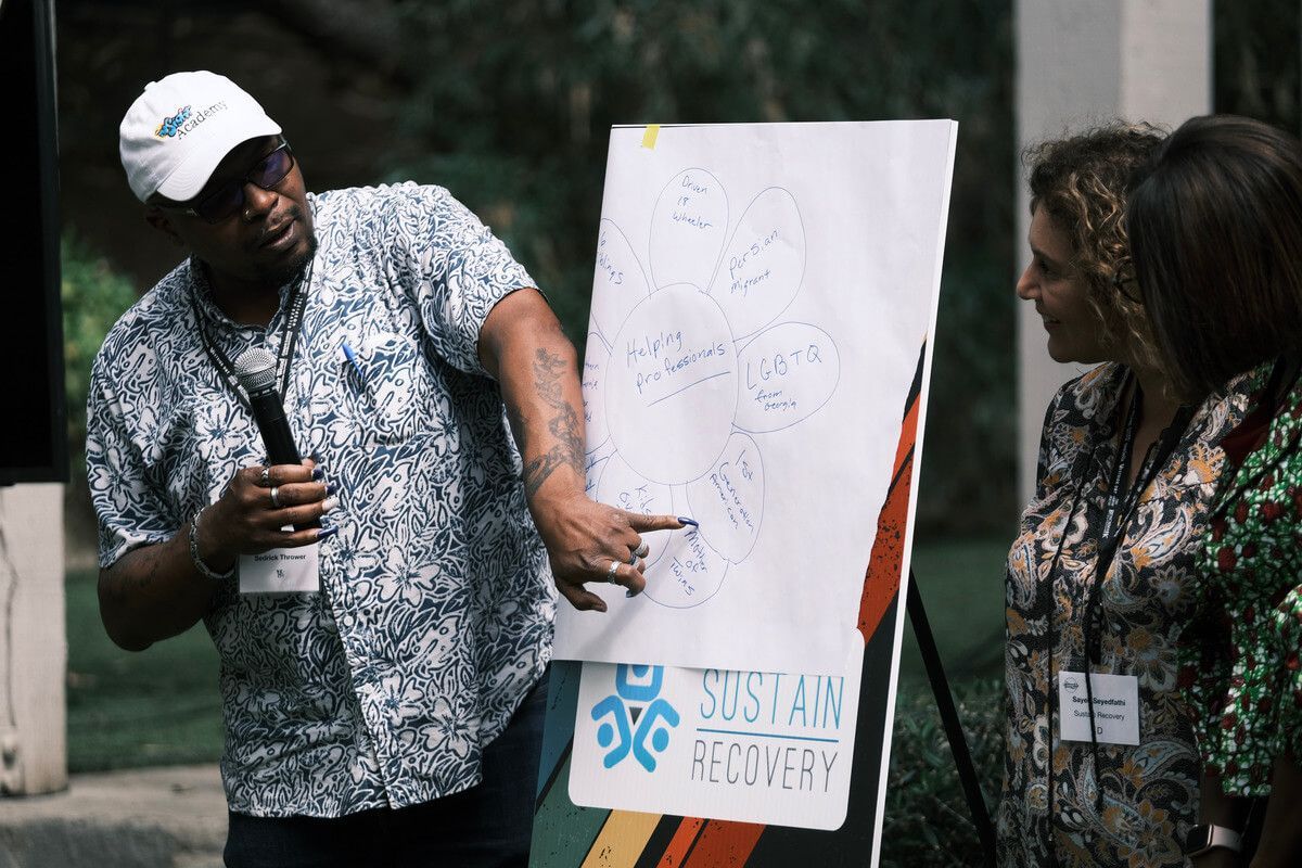 A man is standing in front of a white board with the word sustainable on it.