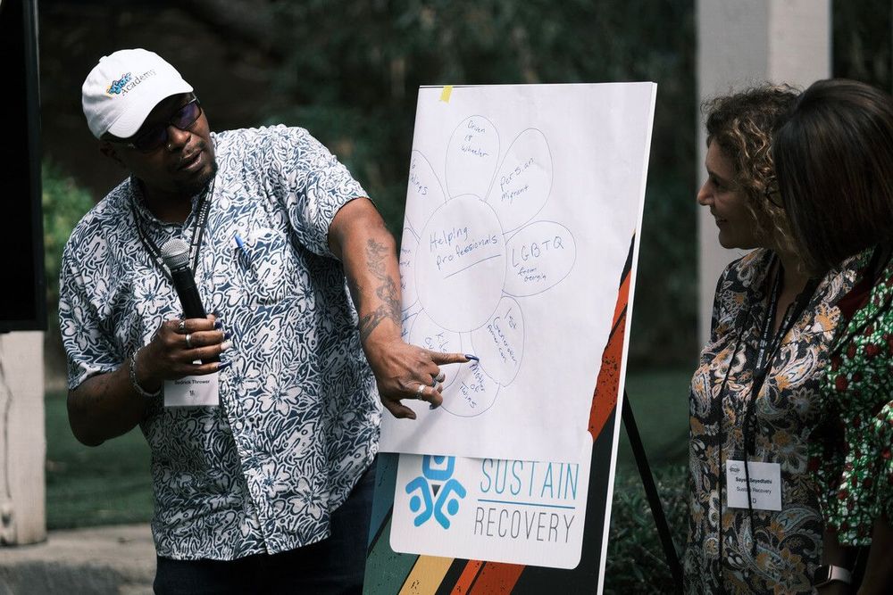 A man is standing in front of a white board with the word sustainable on it.