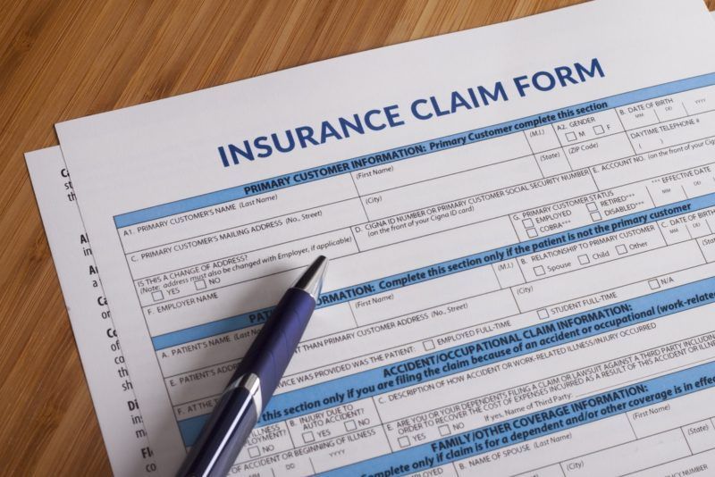 Insurance claim form on a desk with a pen pointing at the form.